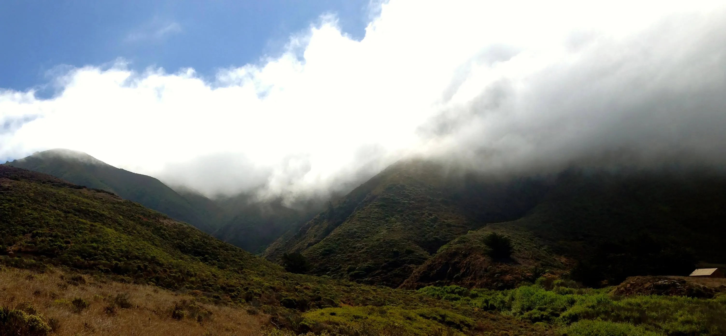 Marine-layer fog spilling over the green Santa Lucia ridgeline above Garrapata